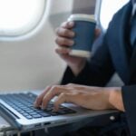 Homem de terno em avião com notebook, conceito de empresário de férias - THICHA SATAPITANON/shutterstock.com