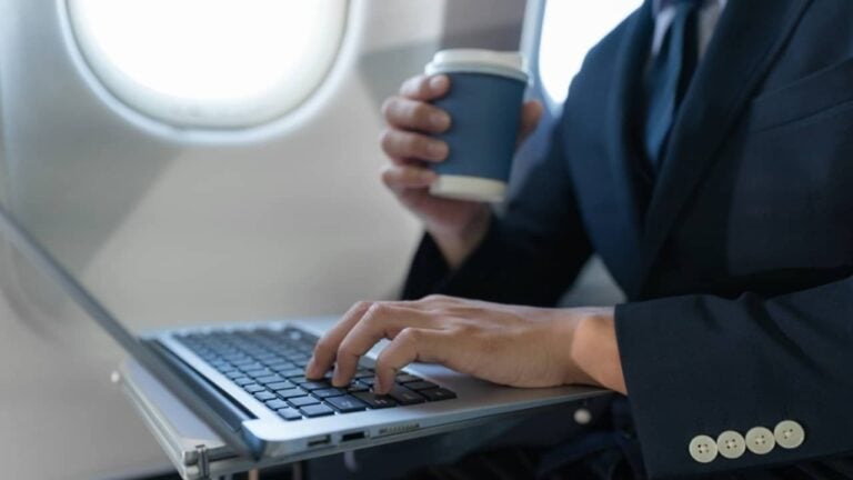 Homem de terno em avião com notebook, conceito de empresário de férias - THICHA SATAPITANON/shutterstock.com