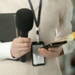 Jornalista com microfone, celular e notebook - New Africa/shutterstock.com