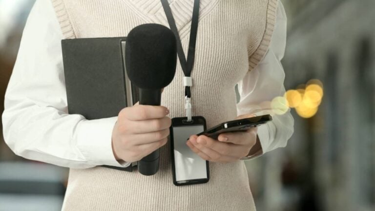 Jornalista com microfone, celular e notebook - New Africa/shutterstock.com