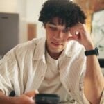 Jovem no telefone - PeopleImages/shutterstock.com