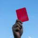 Mão do árbitro segurando cartão vermelho - MihailDechev/ istockphoto.com