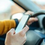 motorista usando celular enquanto dirige - bbernard/Shutterstock.com