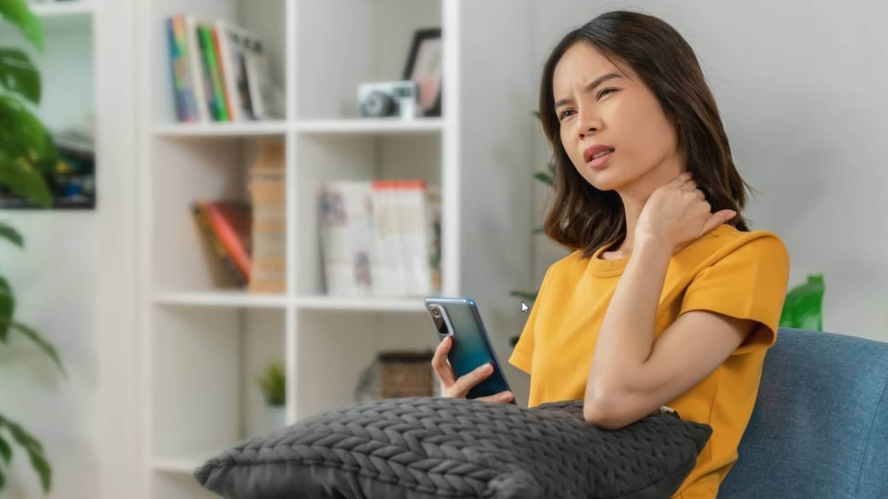 Mulher com dor no pescoço segurando celular - sitthiphong / shutterstock.com