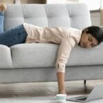 Mulher deitada no sofá, notebook no chão, conceito de cansaço, procrastinação - fizkes/shutterstock.com