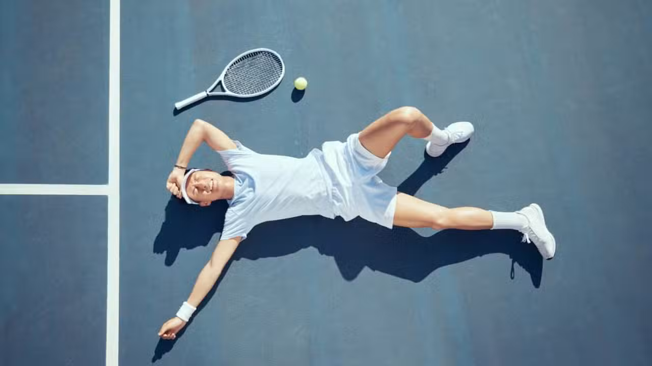 Tenista deitado no chão, cansaço pós treino - PeopleImages / shutterstock.com